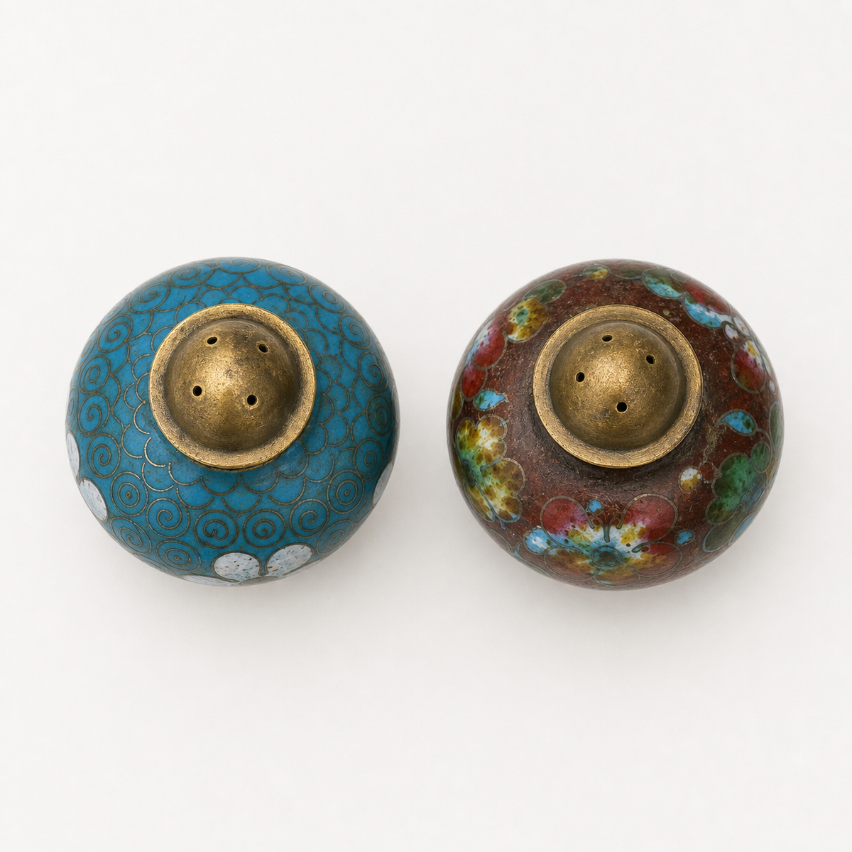 Overhead inspection view of vintage cloisonné spice shaker pair
